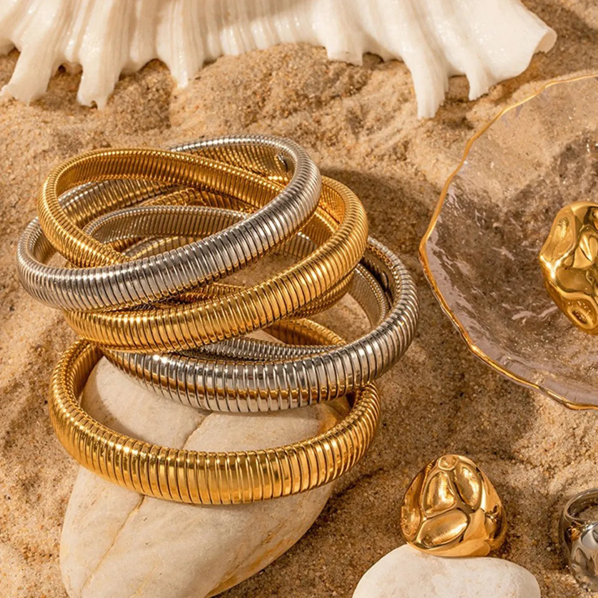 Women's gold titanium steel bracelet with exaggerated vertical stripe ring elastic pattern, showing width options.