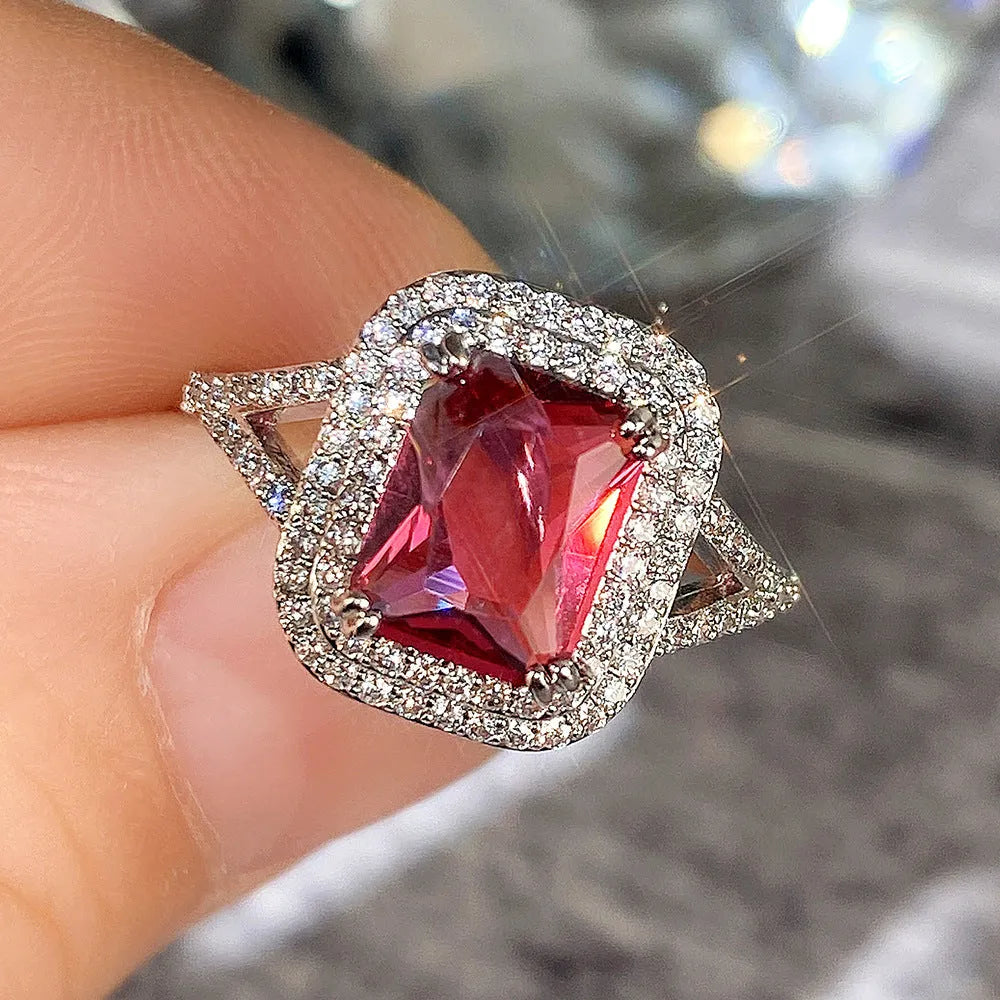 Women's copper square ring with red finish and a central rhinestone, showing geometric design.