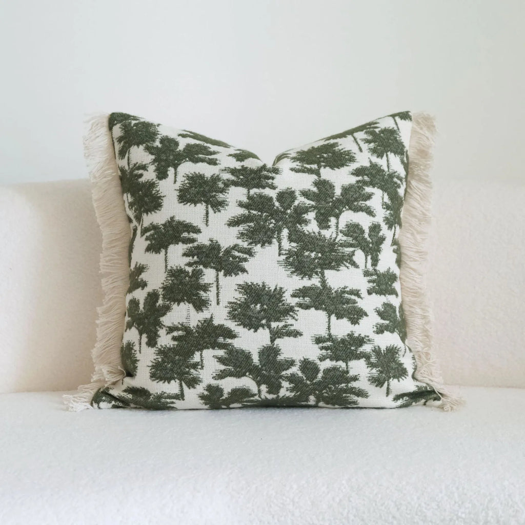 Green cotton and linen hotel pillow with striped or leaf pattern tassel detail on a bed.