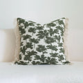 Green cotton and linen hotel pillow with striped or leaf pattern tassel detail on a bed.