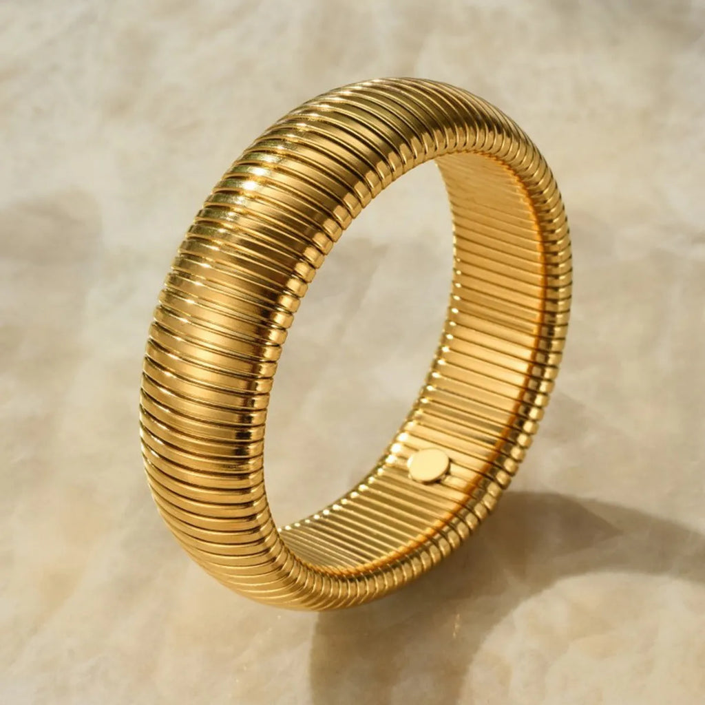 Women's gold titanium steel bracelet with exaggerated vertical stripe ring elastic pattern, showing width options.