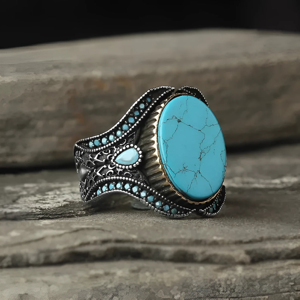 Men's antique silver alloy ring with a round shape and turquoise-coloured centrepiece on a grey background.