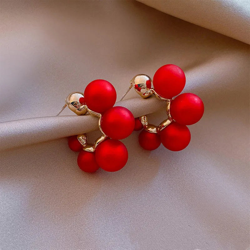 A pair of red dangling bell-shaped alloy earrings for women, also available in white.