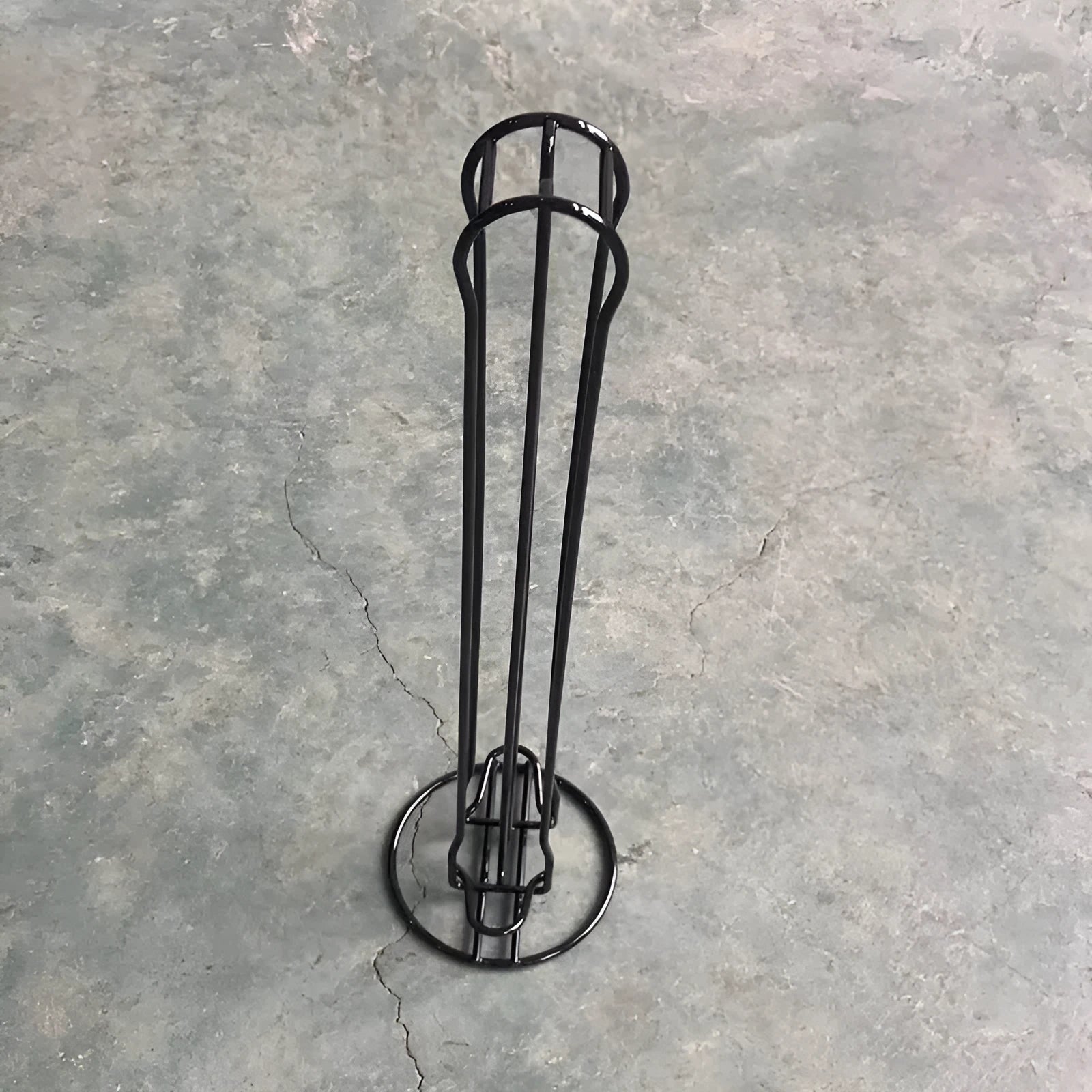 Black wrought iron coffee capsule storage rack holding 20 pods on display shelves.