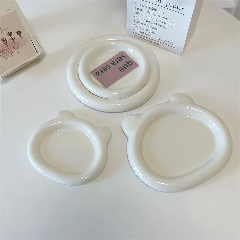 White round porcelain plant plate with a bear doodle design, shown under a small succulent pot.