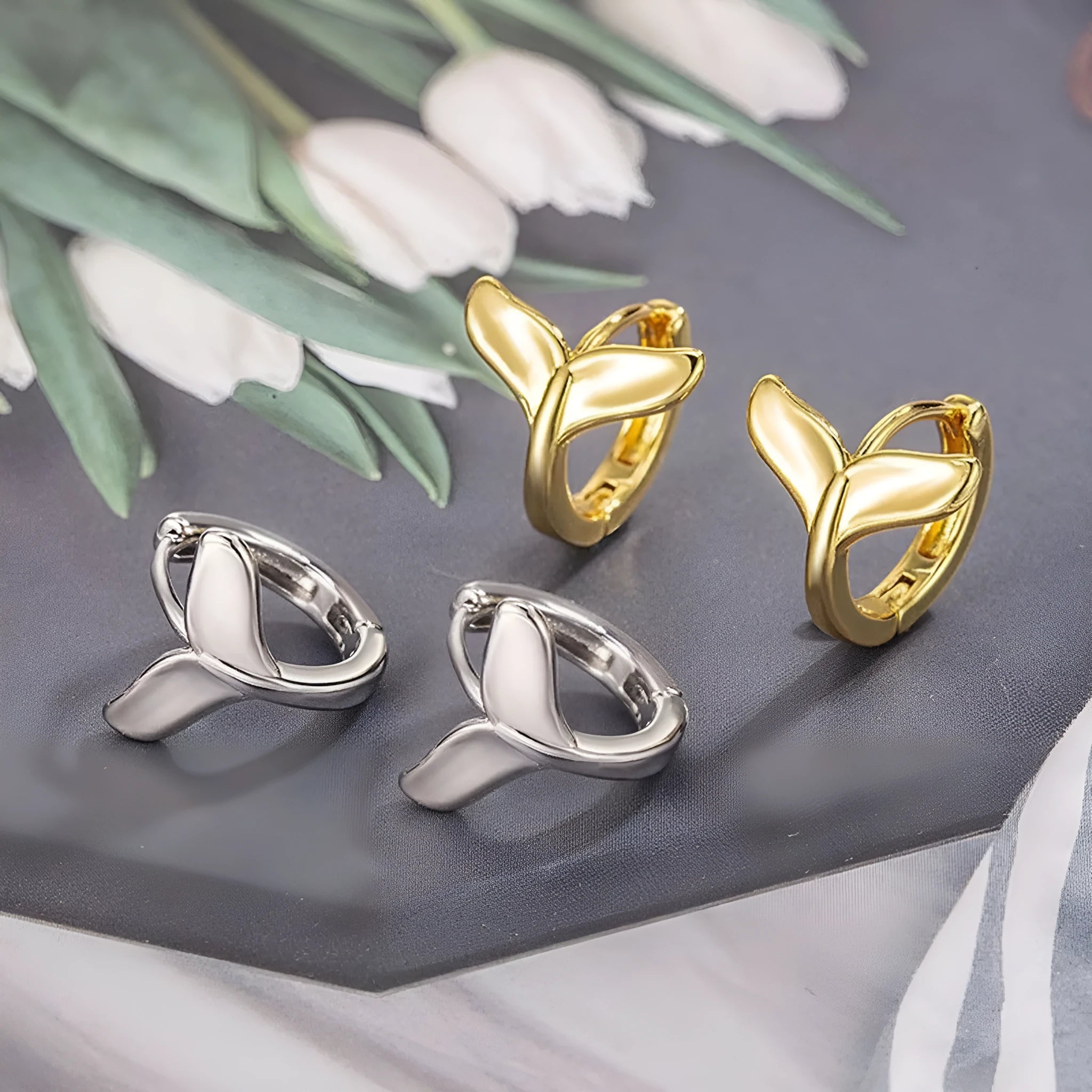 A pair of simple fishtail design earrings with a metallic electroplated finish in either white gold or yellow gold colour.