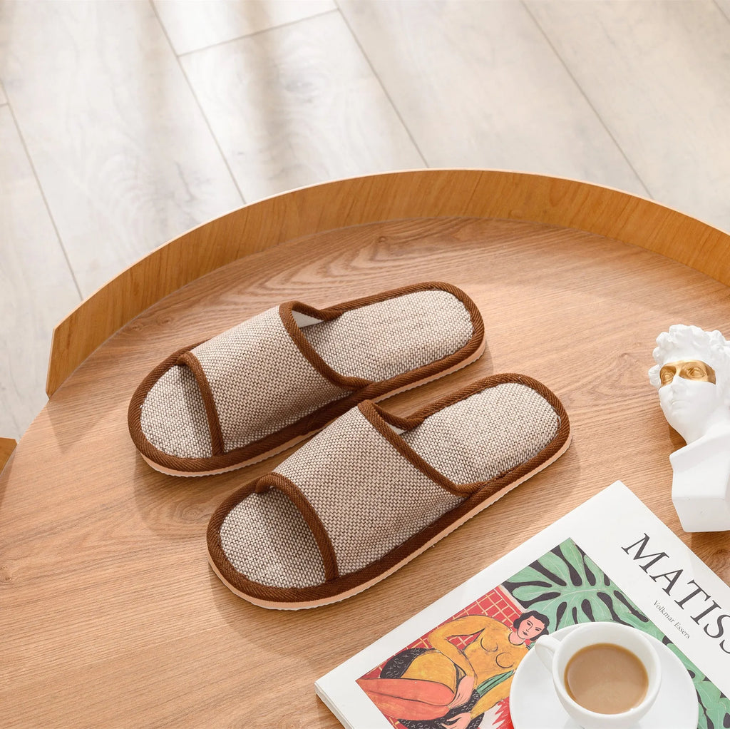Women's open-toe linen slippers in light brown on a wooden floor, showing the breathable design and thickened sole.