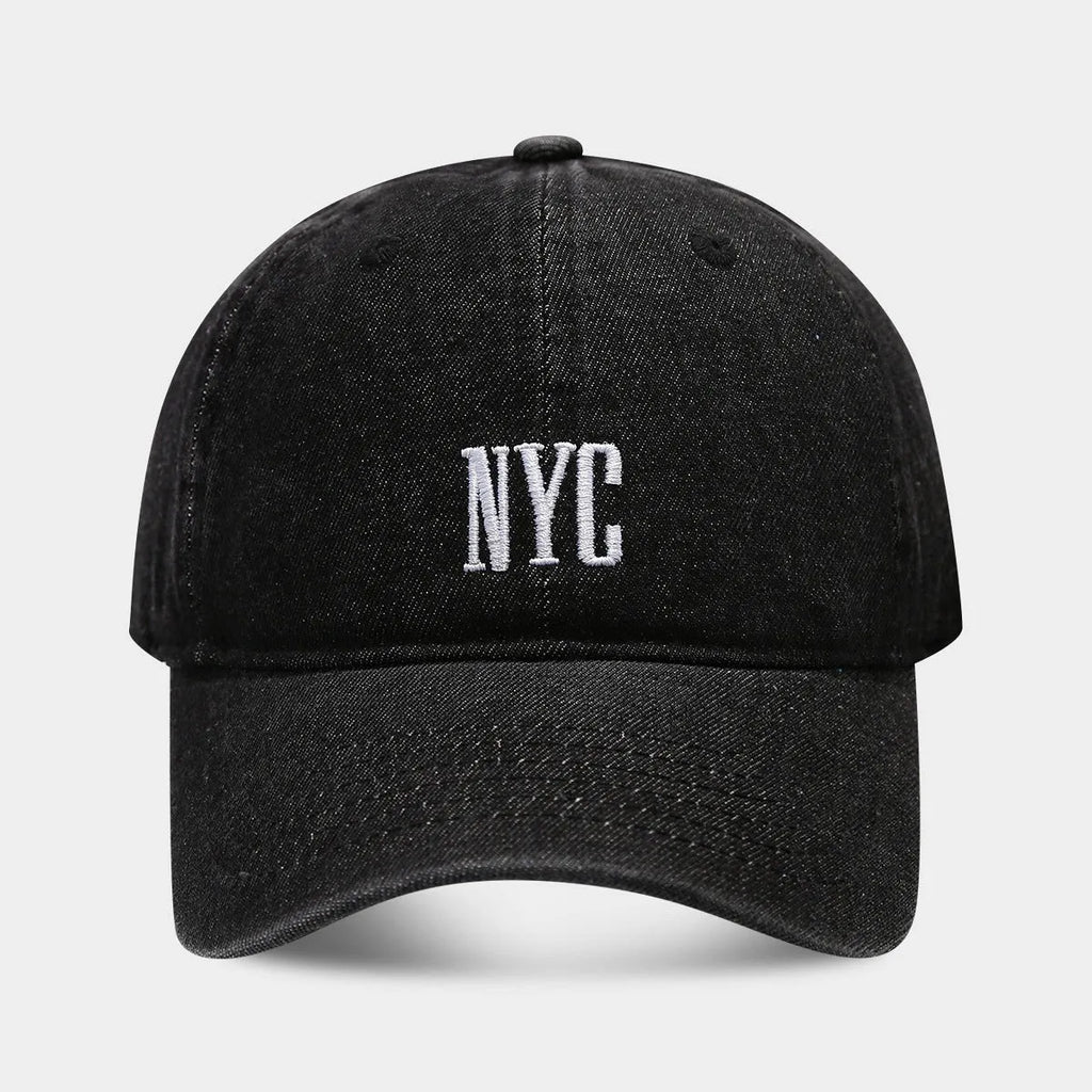 Light blue denim baseball cap with dome crown and printed alphabet letters on the front.