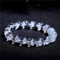 Women's white crystal pyramid bracelet with Ruyi symbols on wrist, showing ground bead texture.