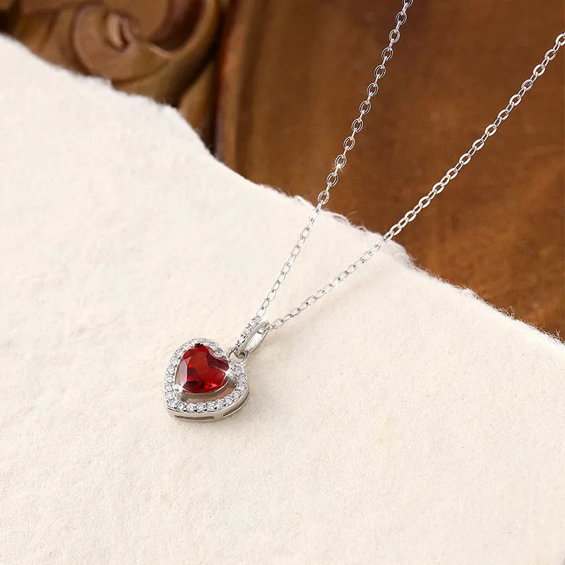 Sterling silver heart pendant necklace with inlaid gemstone on a cross chain for women.