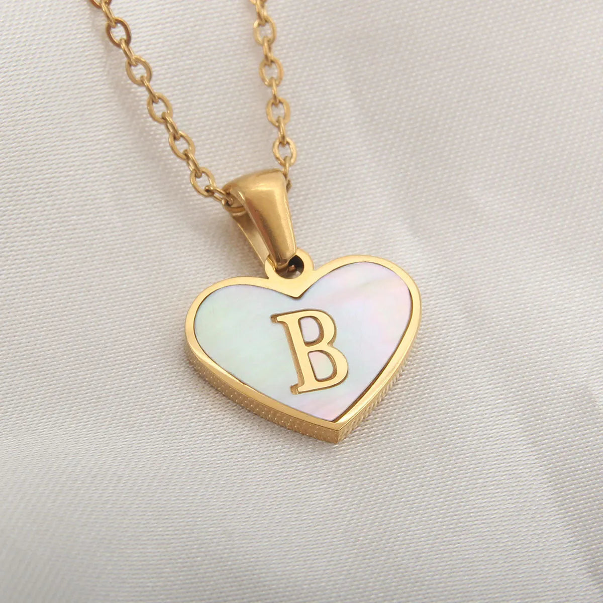Gold-plated heart necklace with white shell pendant and initial personalisation on a stainless steel chain.