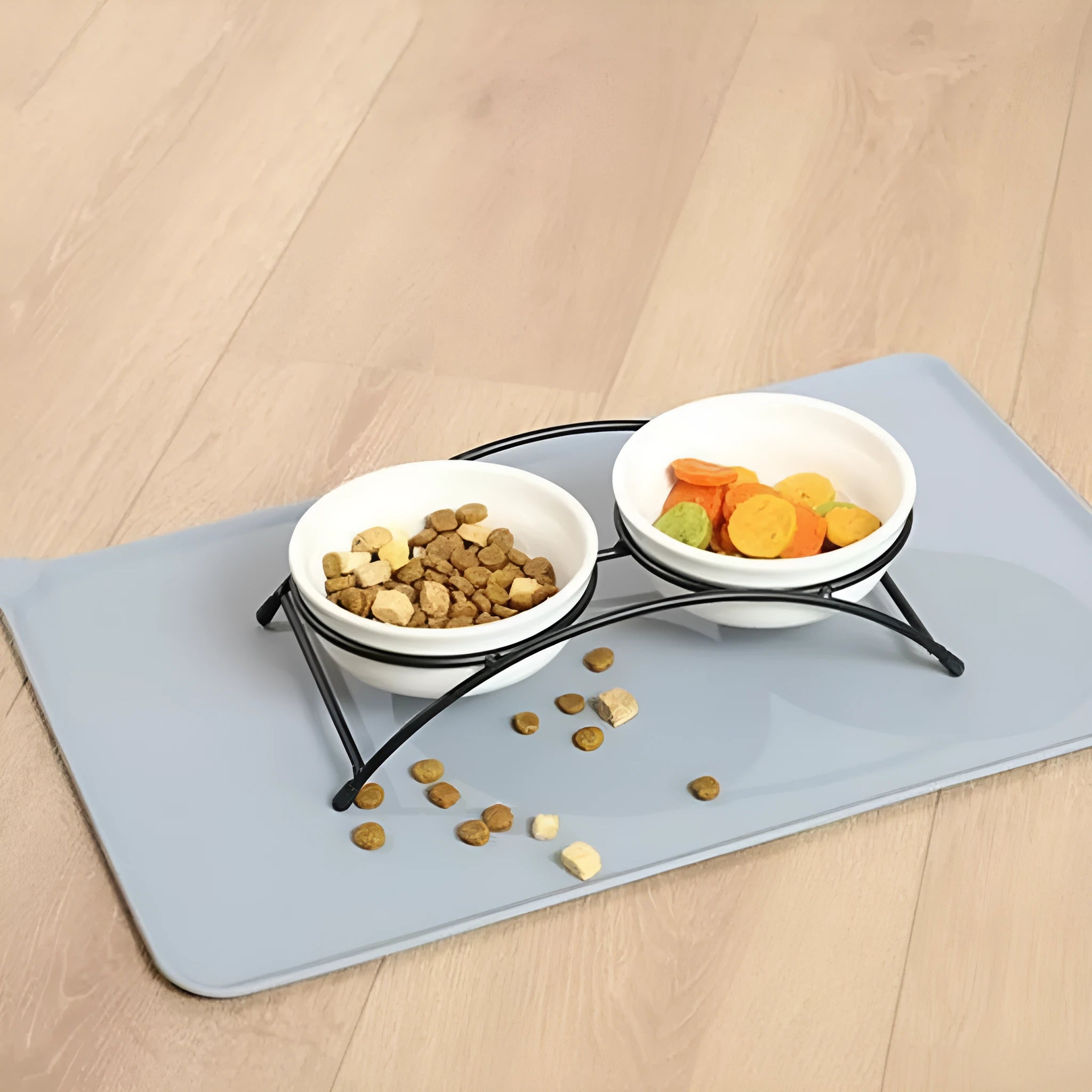 Silicone pet placemat under dog food and water bowls in a grey colour on a wooden floor.