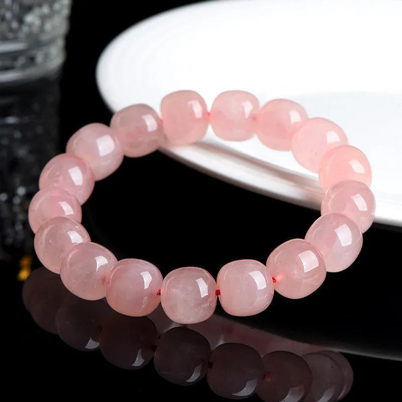 Pink crystal barrel-shaped bead bracelet on a wrist, showing geometric beads and polished finish.