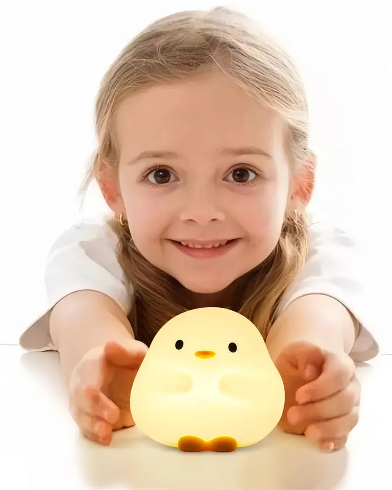 Cute duck shaped LED night lamp with silicone casing and warm light on a bedside table
