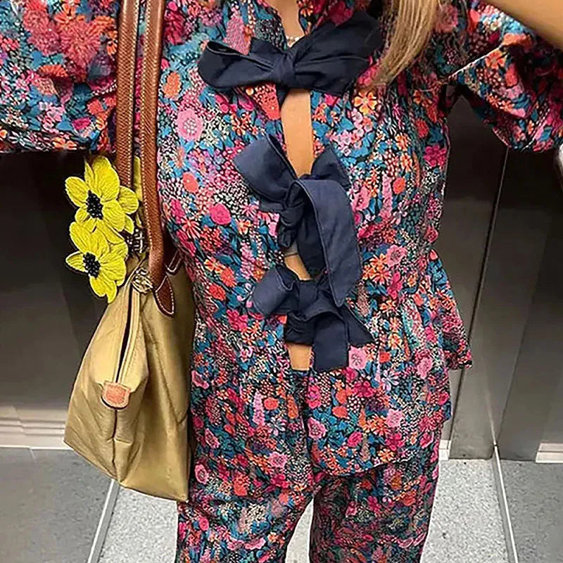 Women's floral print polyester trouser suit with puff sleeve blouse and matching trousers on a hanger.