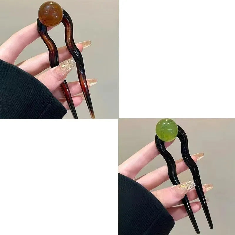 Acrylic U-shaped hair barrette with a small spherical decoration in a beige and caramel two-tone colour combination.