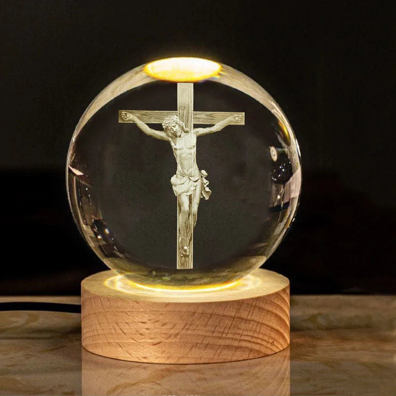 White crystal ball ornament on a wooden warm light base, showing engraved religious symbols.