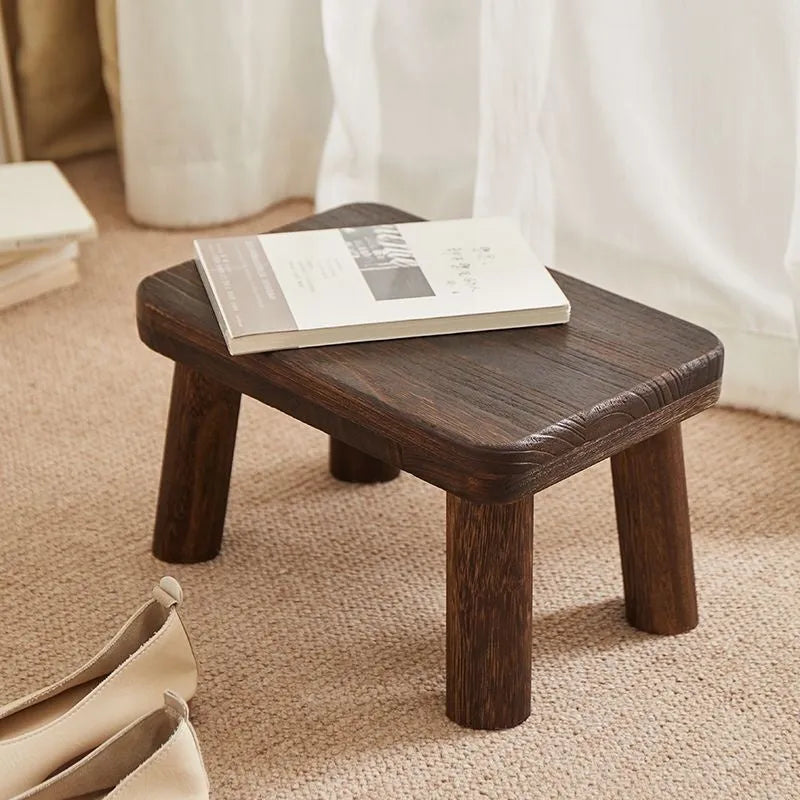 Distressed wooden shoe changing stool with bracket construction in living room setting