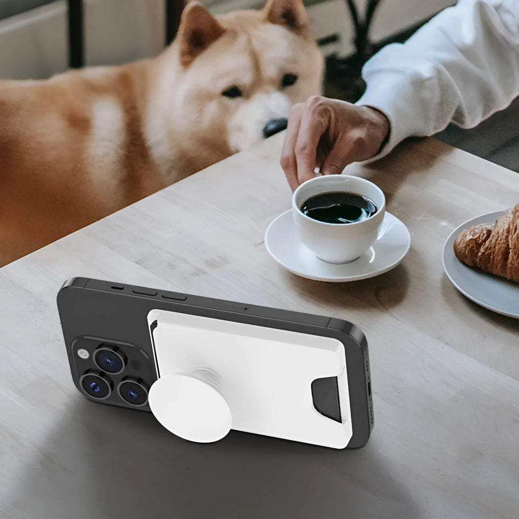 Minimalist black magnetic suction phone holder for iPhone on an office desk.