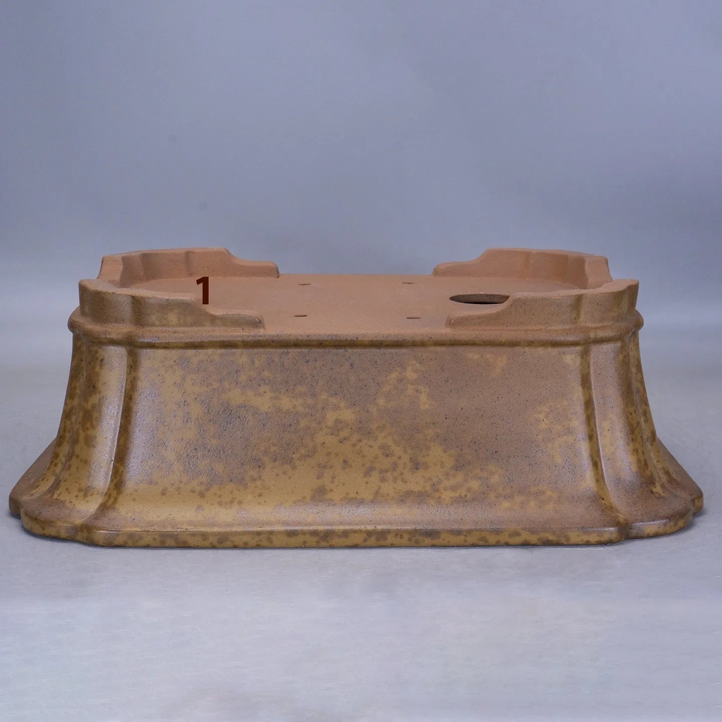 A large rectangular purple sand mud flowerpot with angled segment design on a floor.