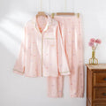 Women's pink cotton long-sleeved pajama top and trousers set laid flat.