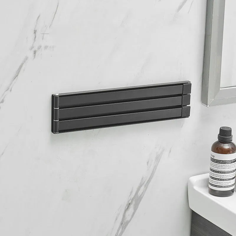 Black folding no-drill towel bar mounted on a bathroom wall with adhesive.