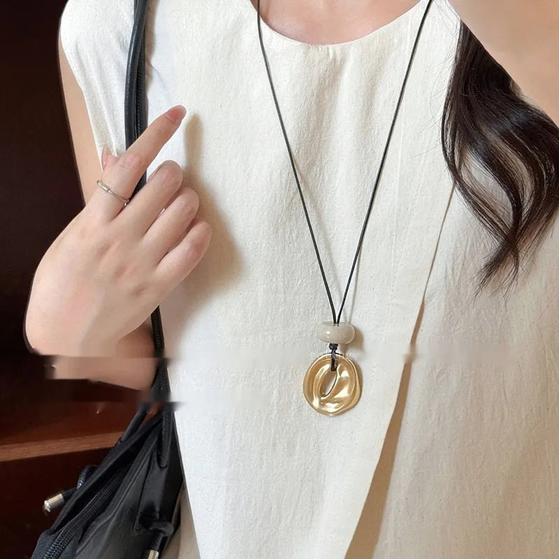 Gold long geometric bow pendant necklace with artificial crystal accents on a white background