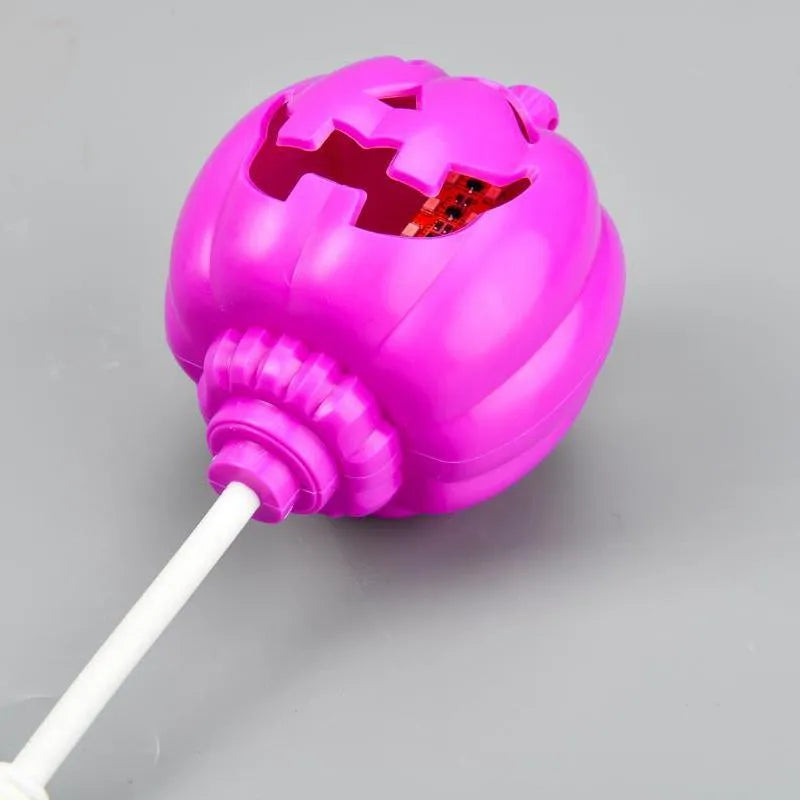 A plastic pumpkin lamp with a USB port, glowing in either yellow or purple light.