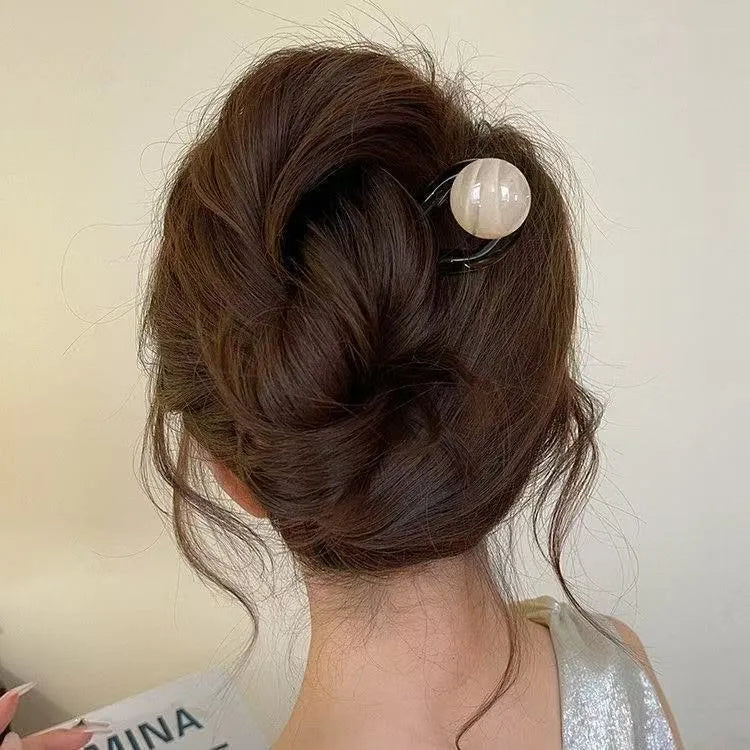 Acrylic U-shaped hair barrette with a small spherical decoration in a beige and caramel two-tone colour combination.