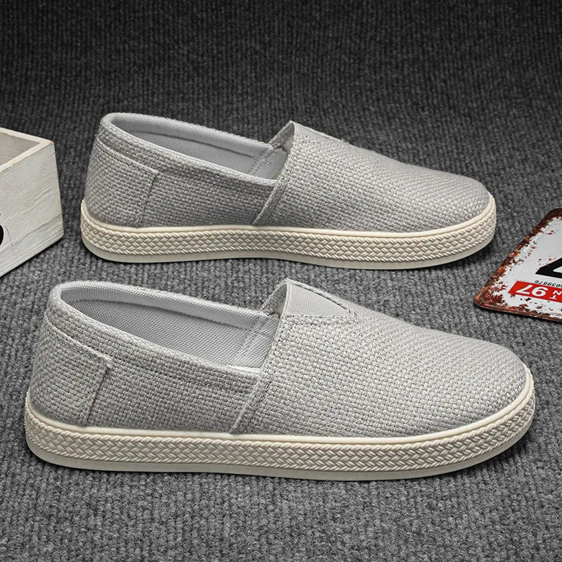 Men's beige canvas slip-on shoes with round toe and PVC sole on a plain background