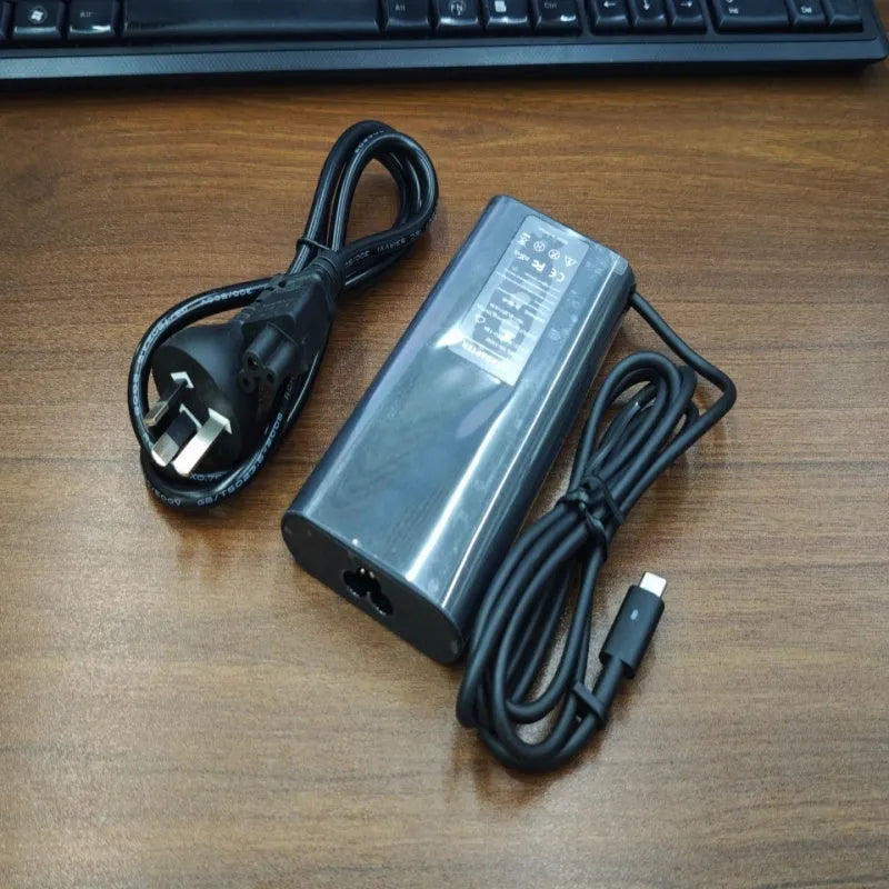 Black 65W USB-C laptop power adapter with multiple international plug attachments