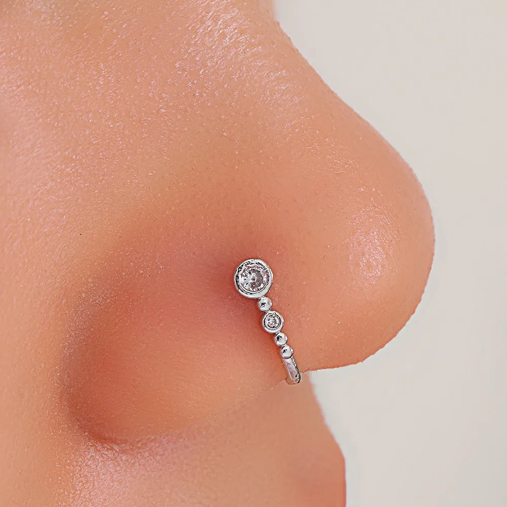 Copper U-shaped nose ring with zircon micro inlay, white K electroplated finish, shown on a flat surface