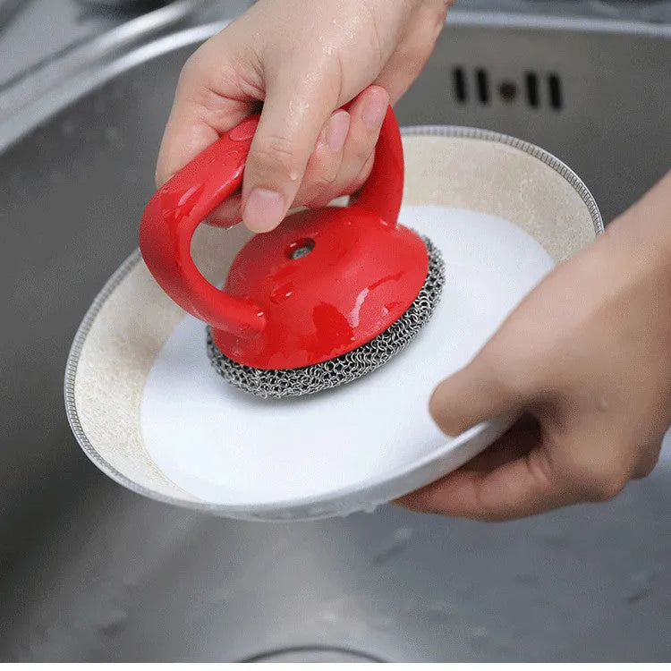 Round 316 stainless steel chainmail scrubber with red silicone handle on cast iron skillet