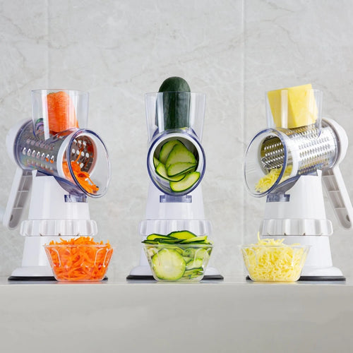 White plastic manual 3-in-1 vegetable slicer grater with stainless steel blades on a kitchen counter.