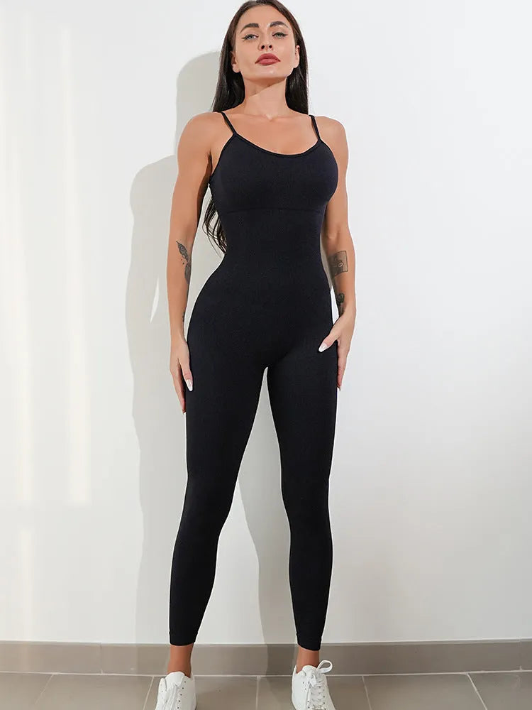 A woman wearing a black sleeveless unitard jumpsuit with spaghetti straps, showing the backless design and close fit.