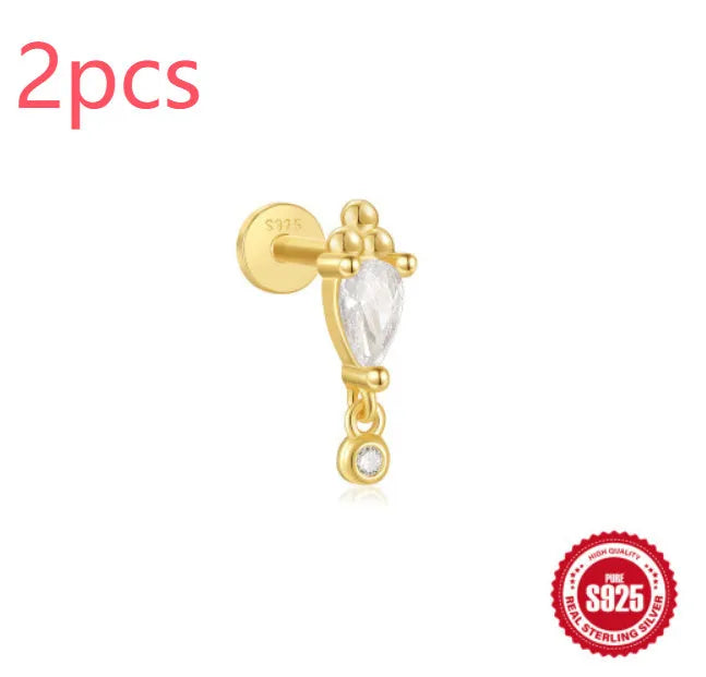 A gold tone sterling silver ear stud featuring a dangling tassel and XINGX inlaid design on the stud.