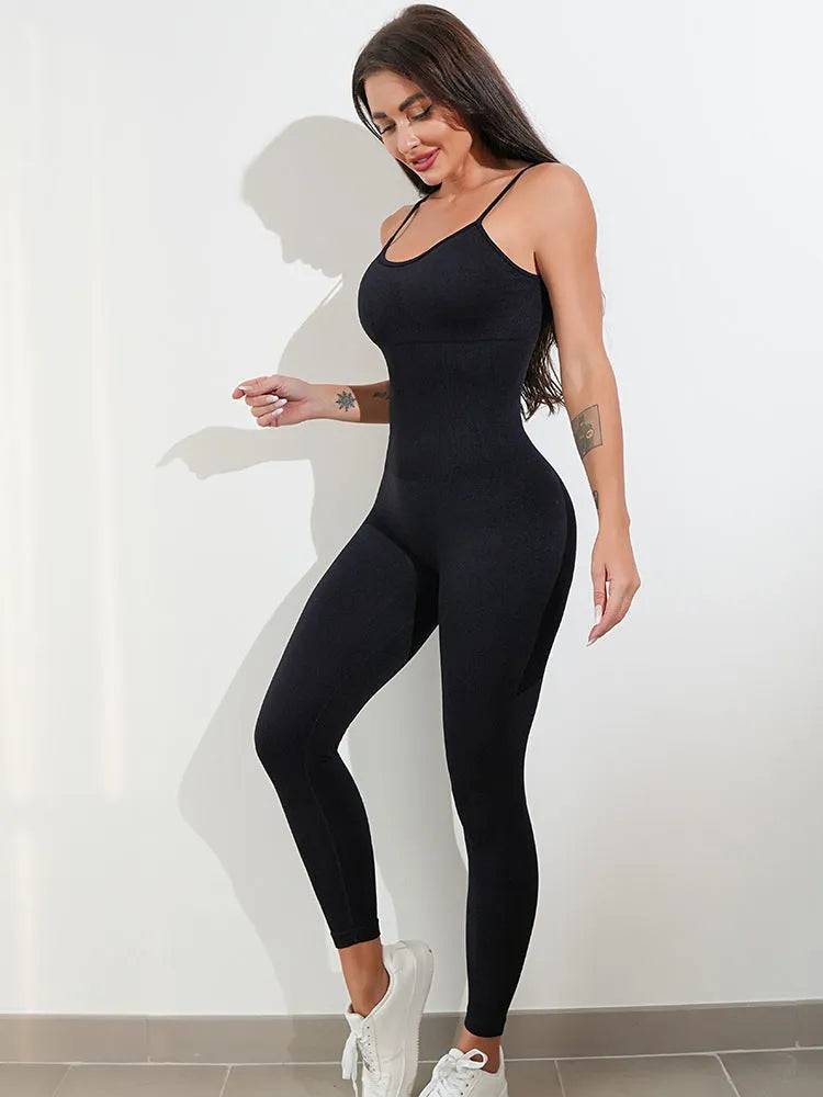 A woman wearing a black sleeveless unitard jumpsuit with spaghetti straps, showing the backless design and close fit.