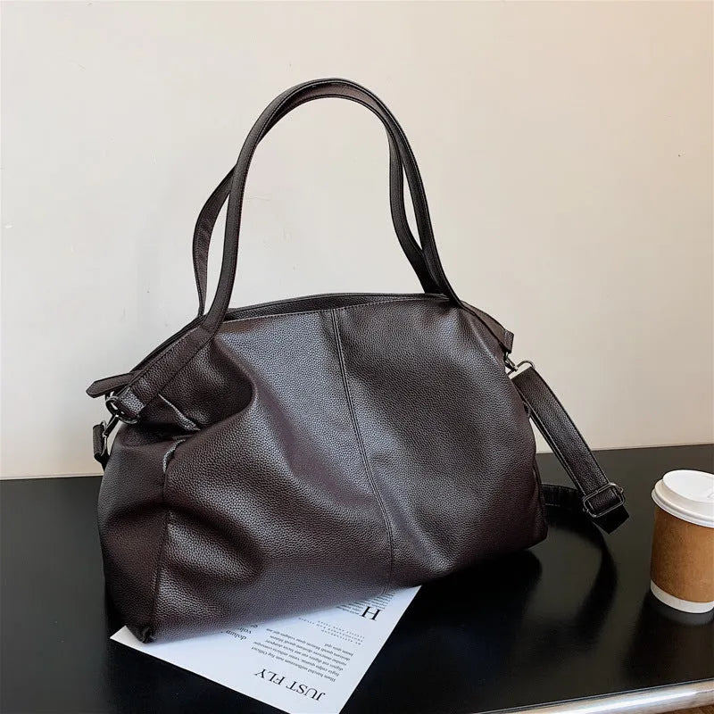 Soft black casual messenger tote bag with zip, showing internal phone pocket and adjustable long shoulder strap.