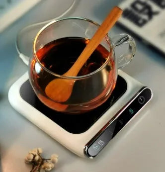Black USB cup warmer on a desk next to a coffee mug, showing control panel.
