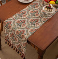 Long blue ginkgo leaf patterned table flag with tassels draped over a wooden sideboard.