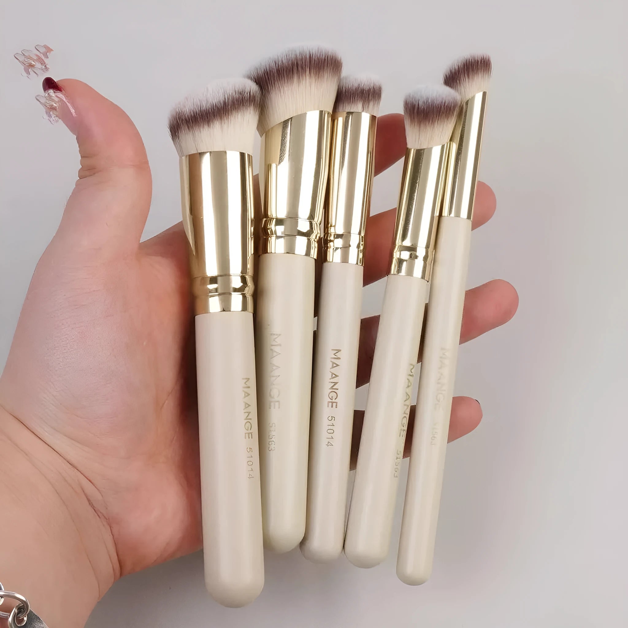 Apricot coloured MAANGE angled blush brush and 4-piece makeup brush set on white background