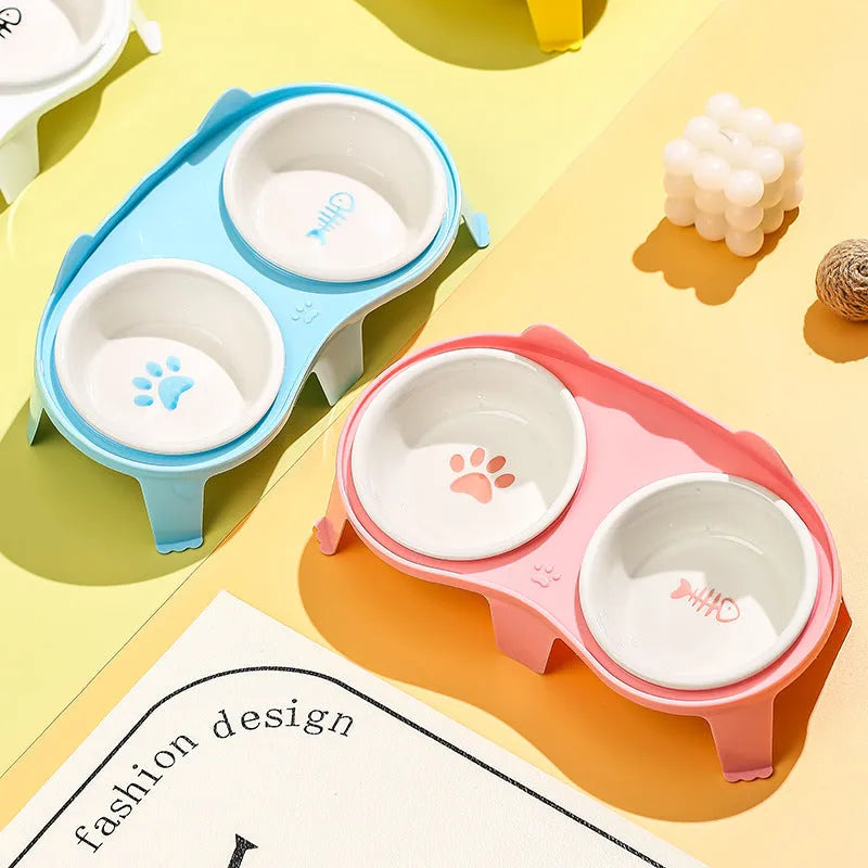 Blue ceramic cat food and water bowls on a white elevated plastic stand with a hook