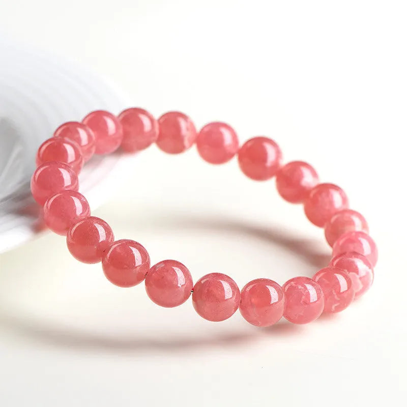 Women's geometric Rhodochrosite crystal bracelet with Longevity Lock feature on a wrist, showing red patterned stone beads.