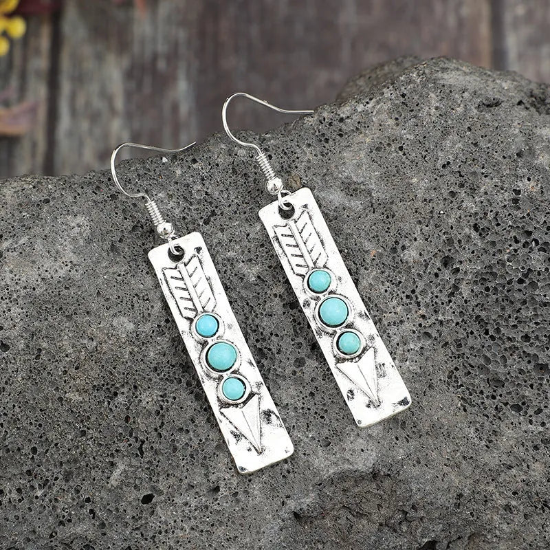 Geometric silver earrings with turquoise inlay pattern and retro styling on long strip design