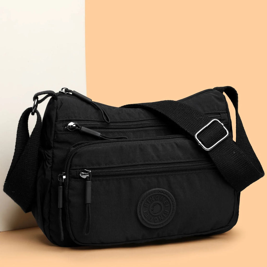 Water-repellent nylon crossbody cloth bag showing internal zipper compartments and shoulder strap