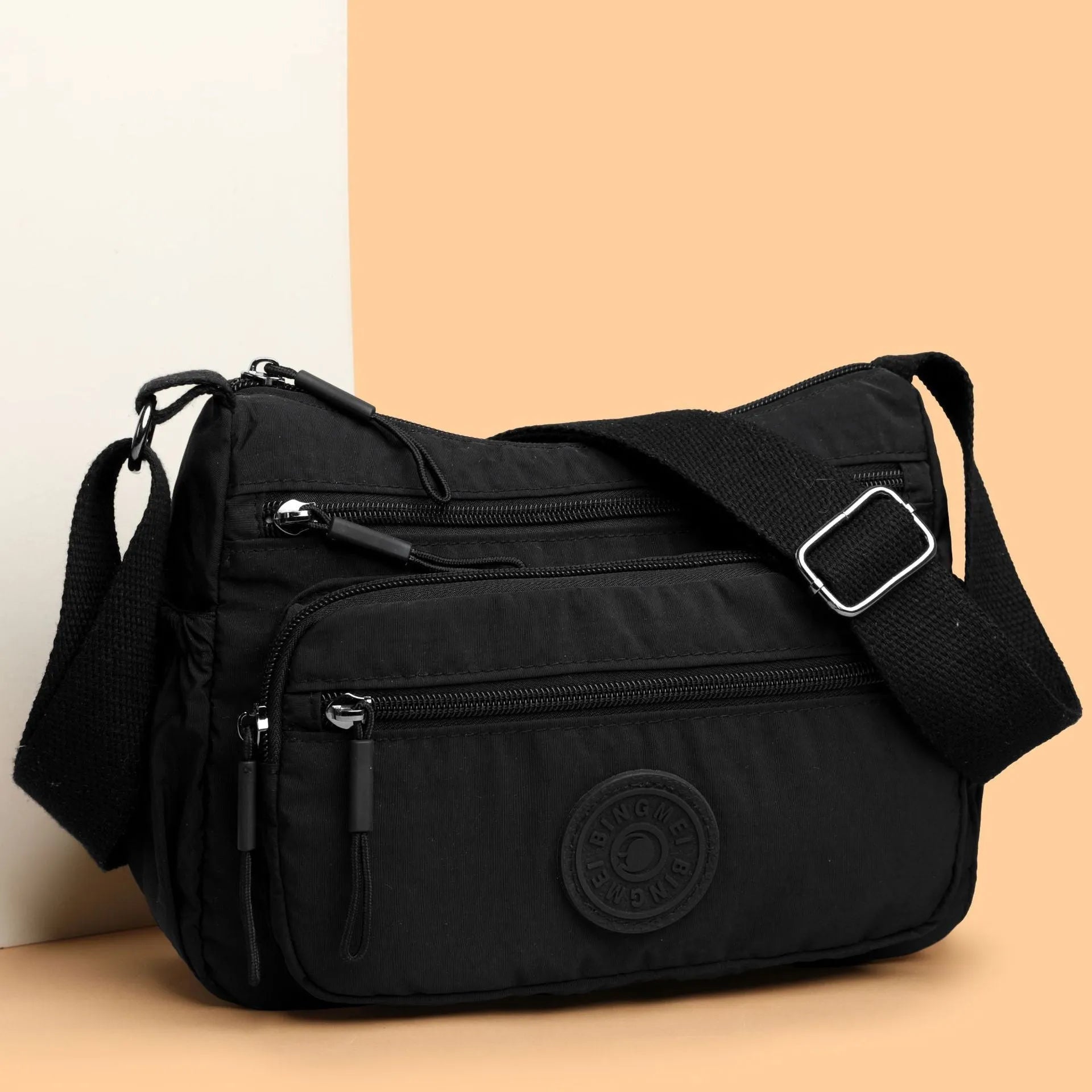 Water-repellent nylon crossbody cloth bag showing internal zipper compartments and shoulder strap