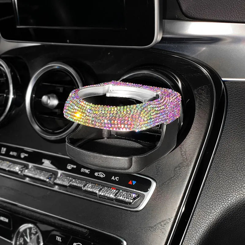 White diamond rhinestone car air vent cup holder bracket on a grey car dashboard.