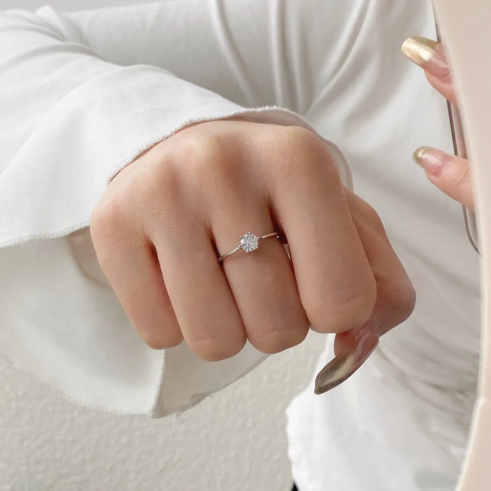 Sterling silver ring with six-claw zircon setting and open mouth adjustable band on white background