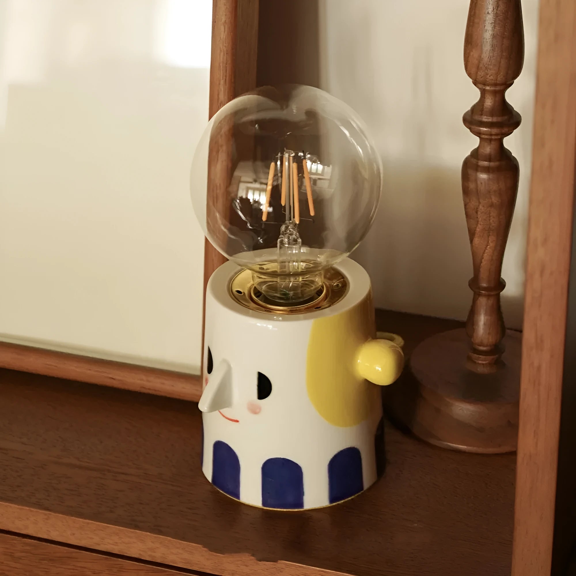 Handmade ceramic lamp with ball headlight design on wooden surface