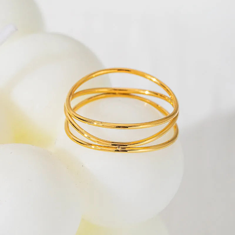 Gold titanium steel women's ring with a three-layer geometric line and coiled design on a white background.
